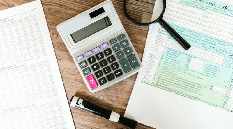 gray calculator and black magnifying glass on brown wooden surface