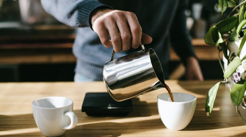 person pouring coffee in white ceramic mug