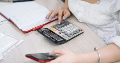 woman using a black and red smartphone and calculator