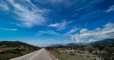 a road with a blue sky and clouds