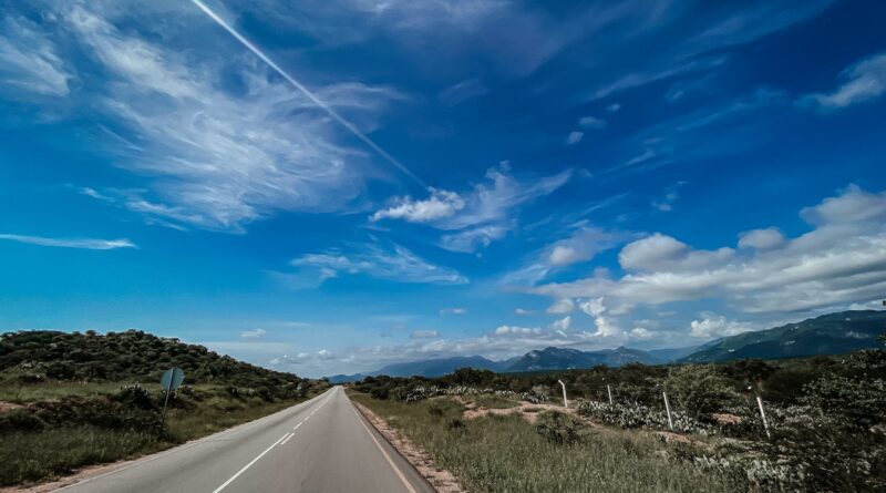 a road with a blue sky and clouds