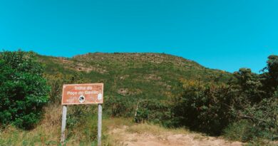 a sign on a dirt road with a mountain in the background