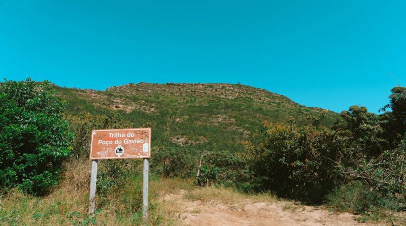a sign on a dirt road with a mountain in the background